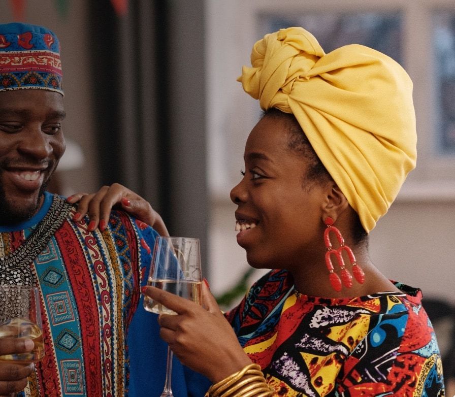 A couple in traditional attire, laughing together over a drink